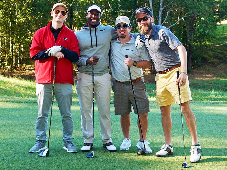 Four men with golf clubs standing together at an 大象tv golf event