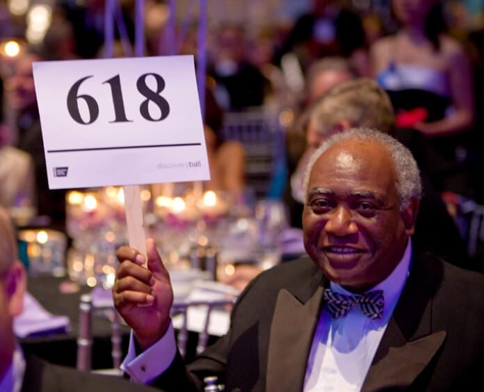 elderly black male bidding during black tie gala event