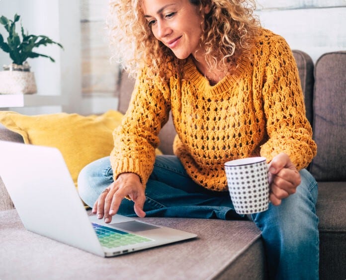ambiguous woman looking at computer with coffee mug