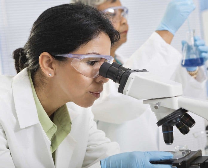 Female researcher looking through microscope in lab